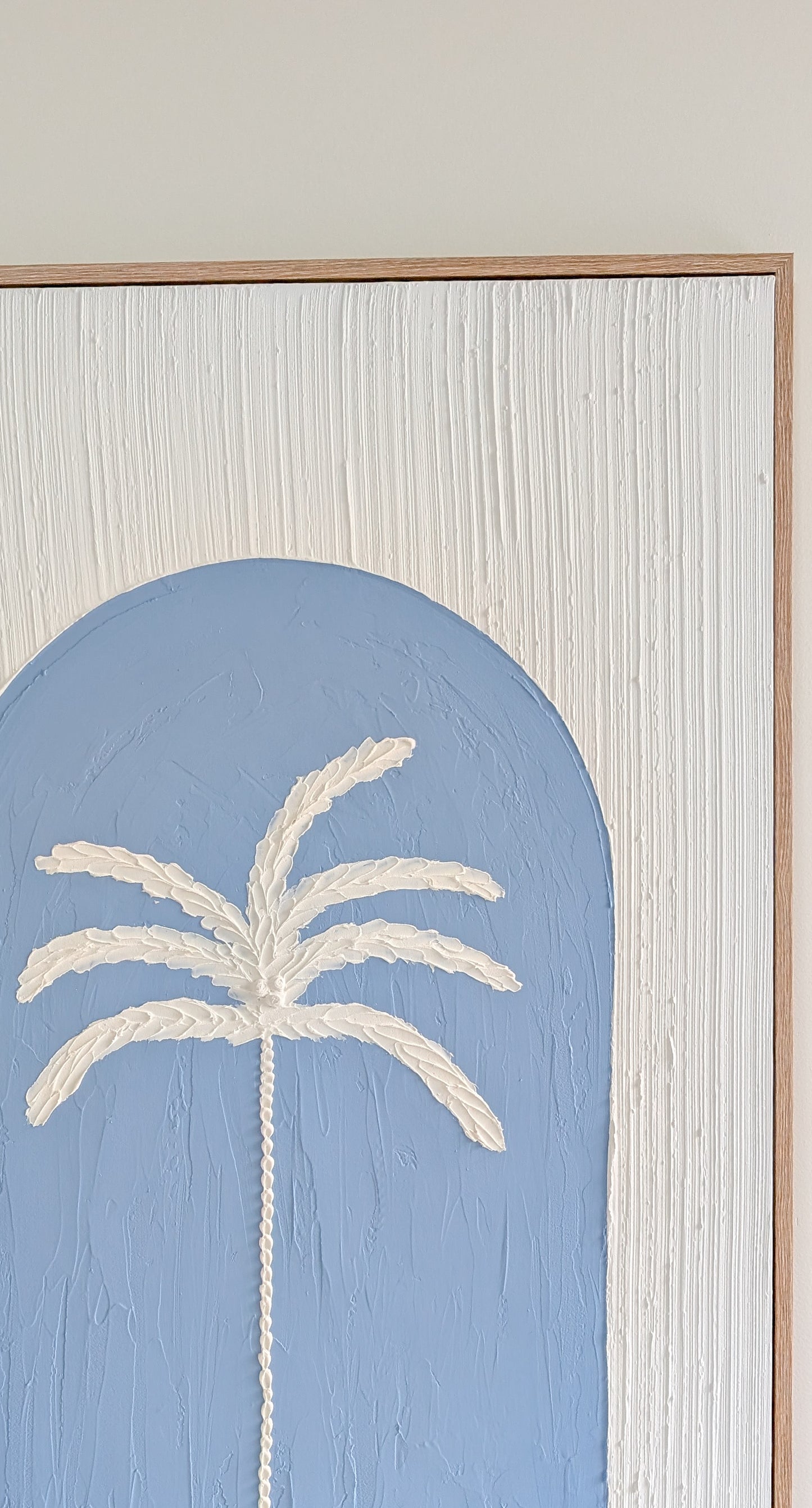 Framed artwork with a palm tree design on a light blue background