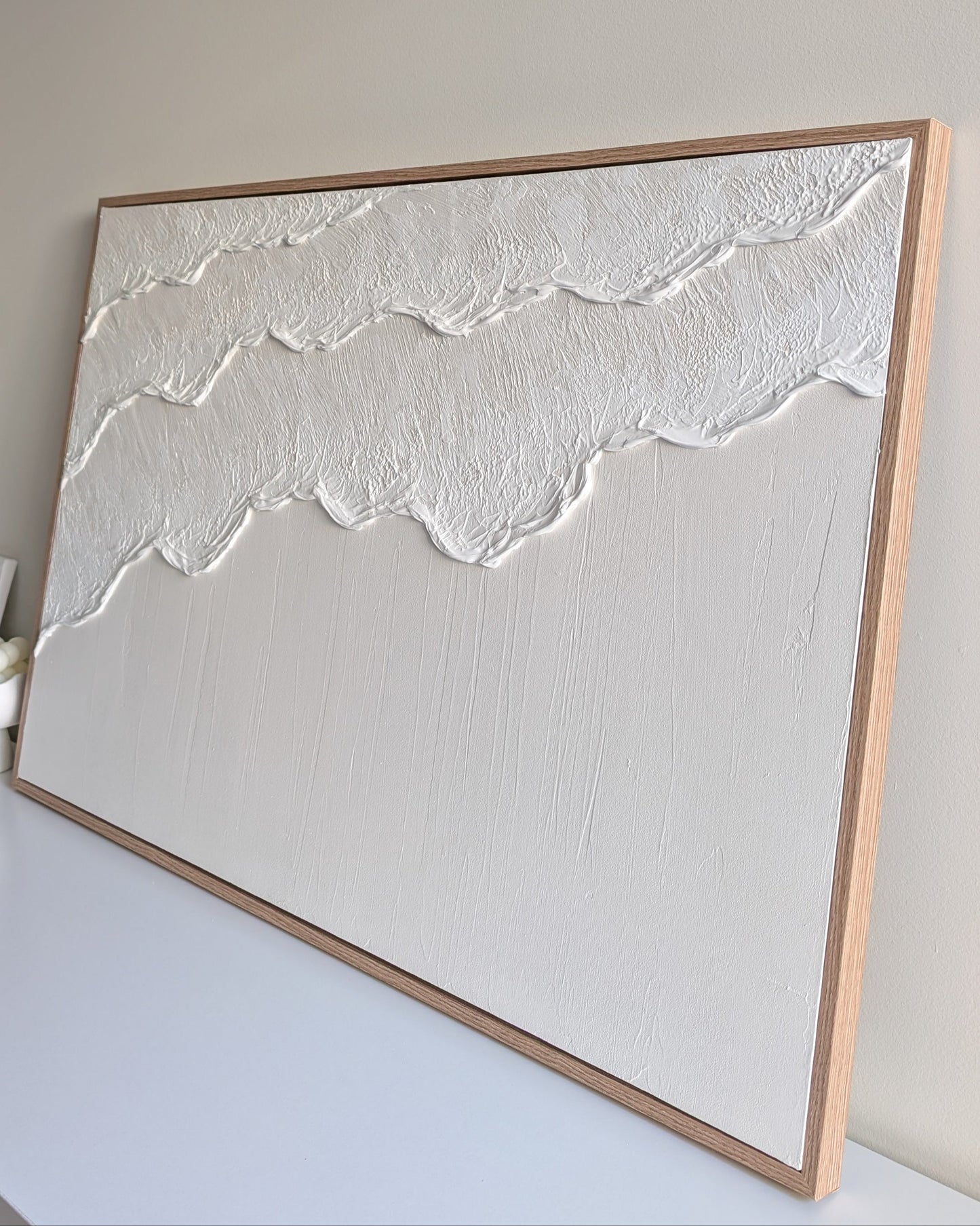 Framed artwork with textured white design on a plain background