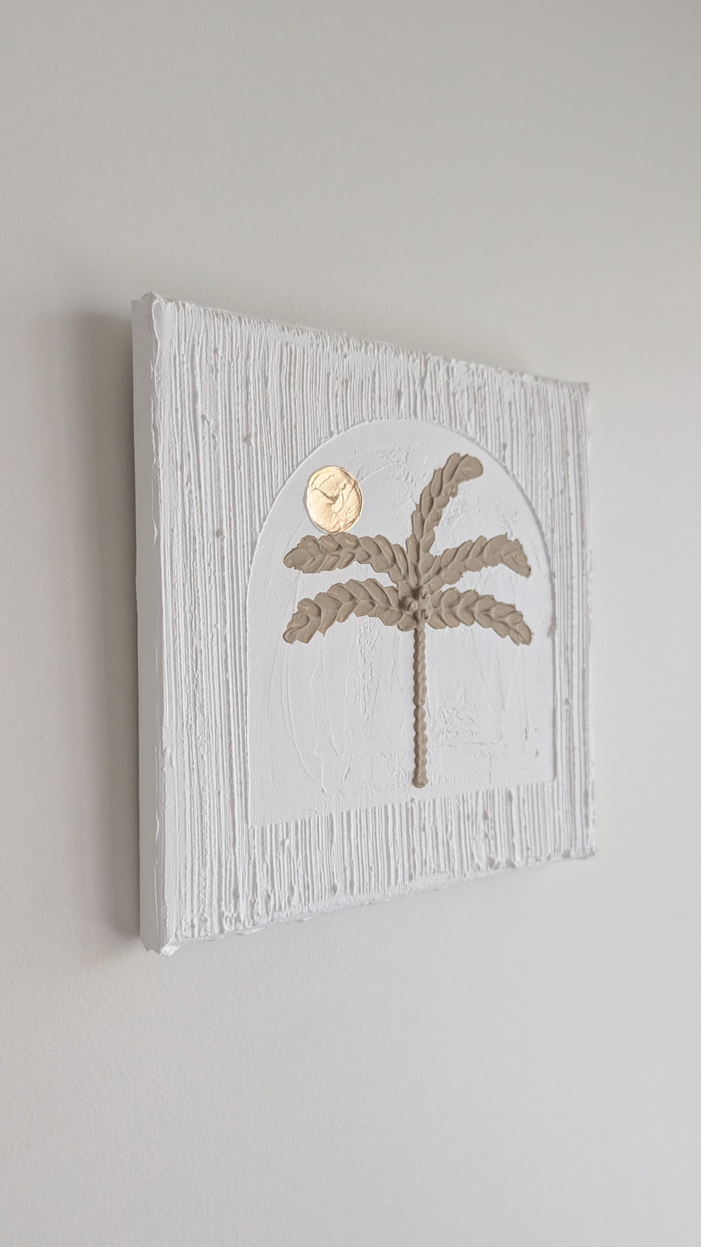Decorative wall art with palm tree design on a light gray background
