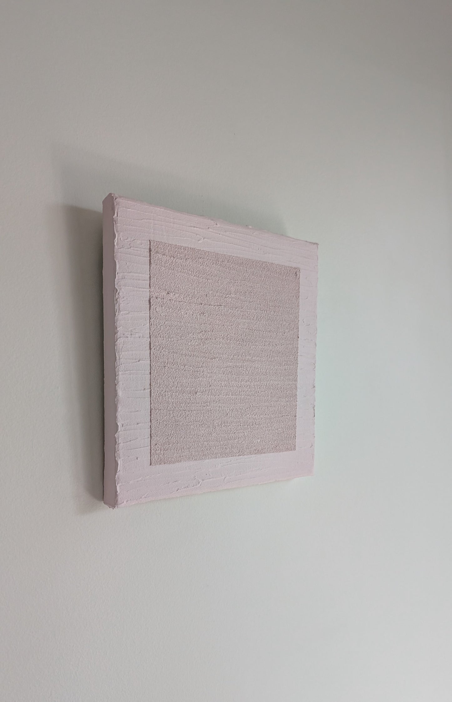 Textured pink wall art piece on a plain white wall