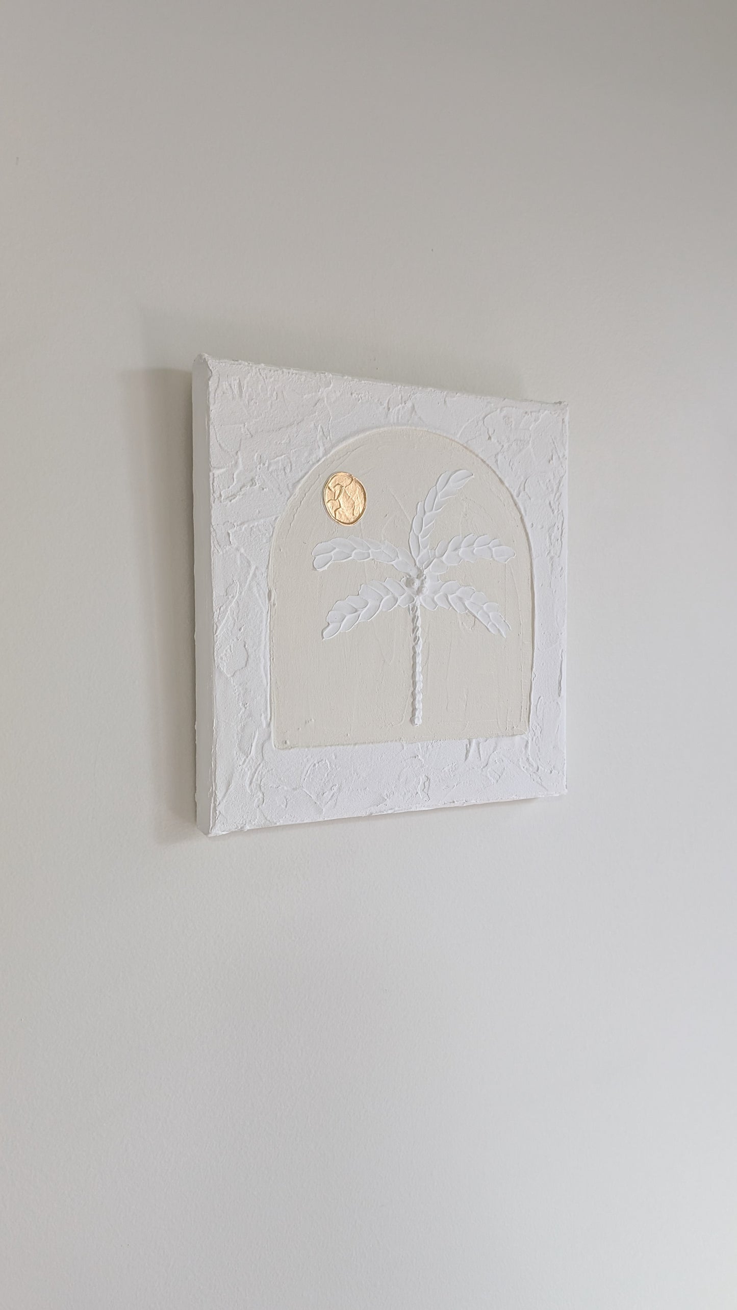 Decorative wall art with palm tree and moon design on a plain wall