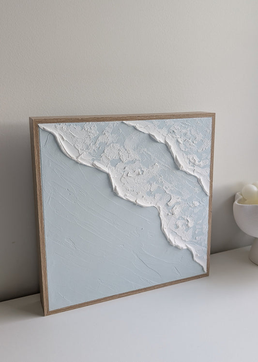 Handmade coastal wave textured wall art with natural timber frame, angled view against white wall