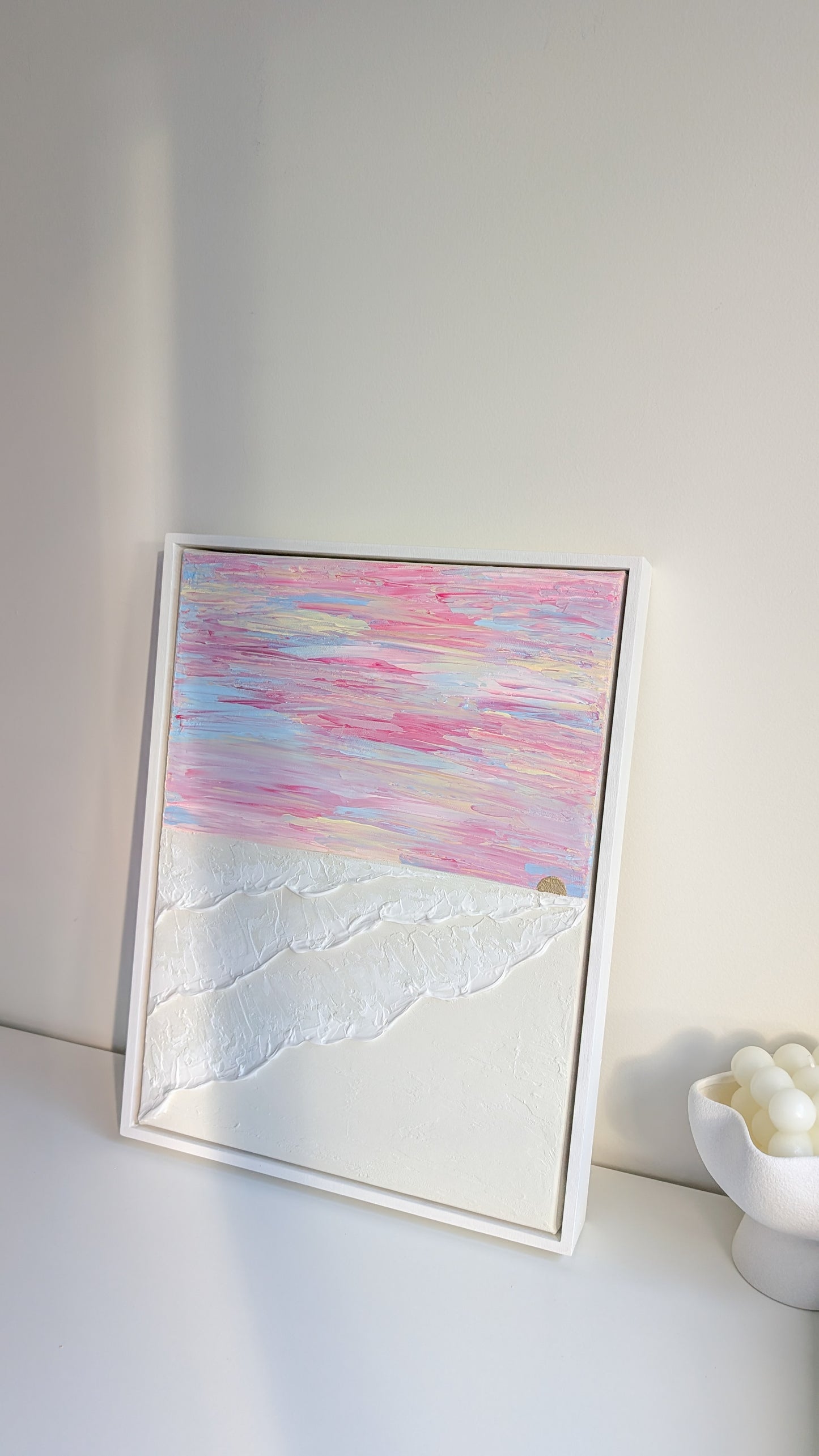Original coastal wall art with layered texture and soft pink sunset sky, framed in white wash wood.