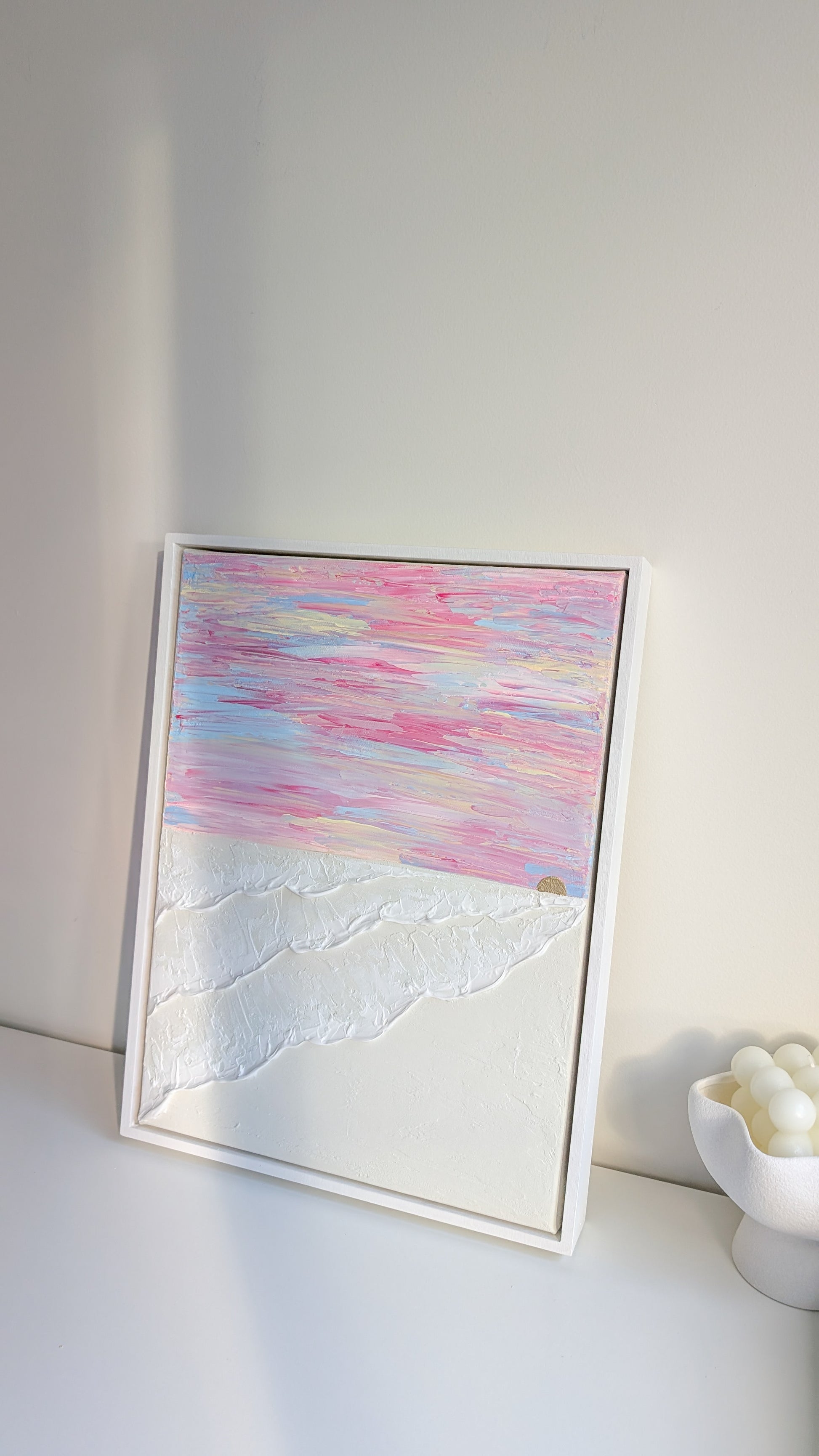 Original coastal wall art with layered texture and soft pink sunset sky, framed in white wash wood.