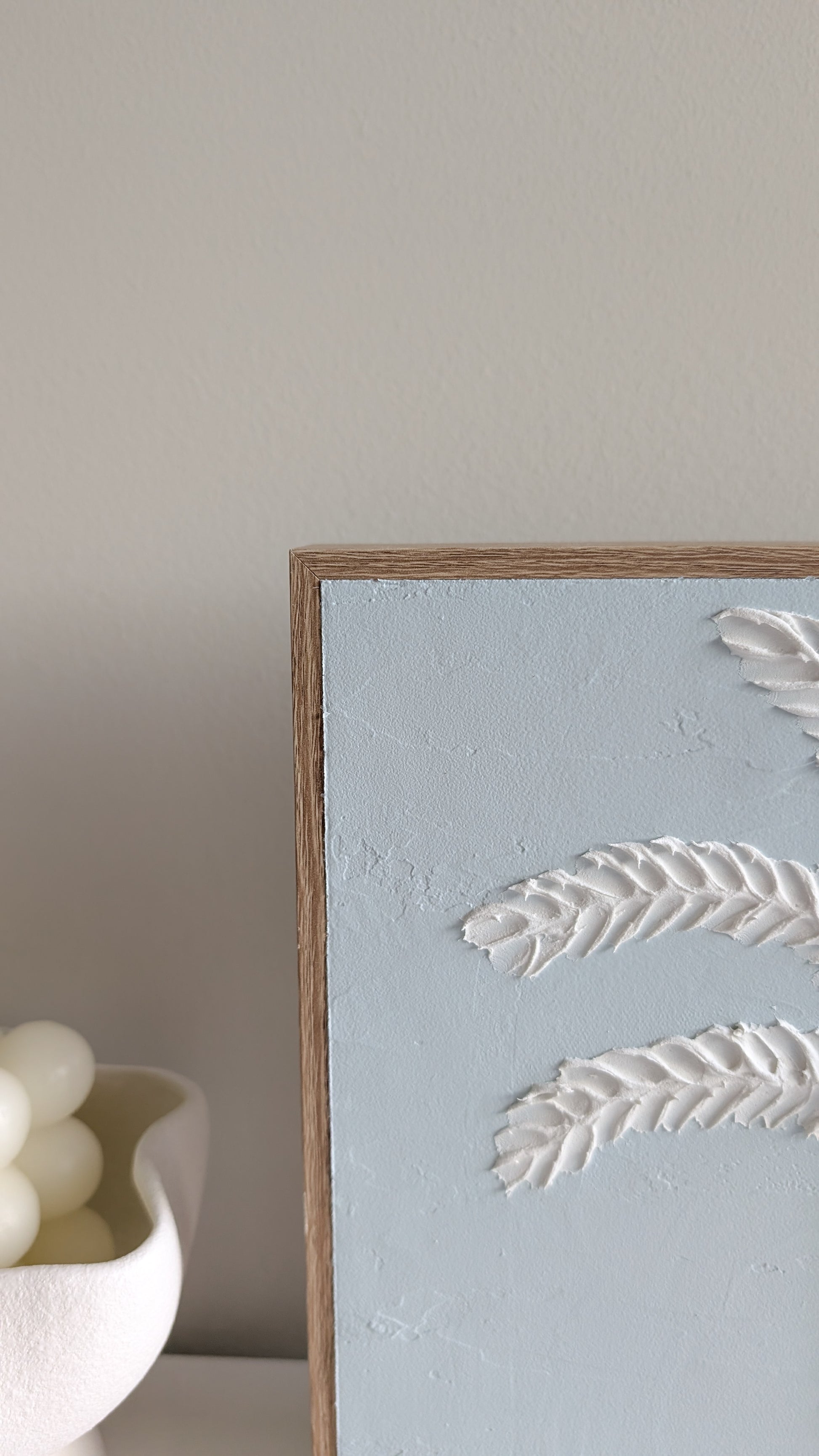 Close-up of palm tree textured wall art with coastal blue background and 3D design