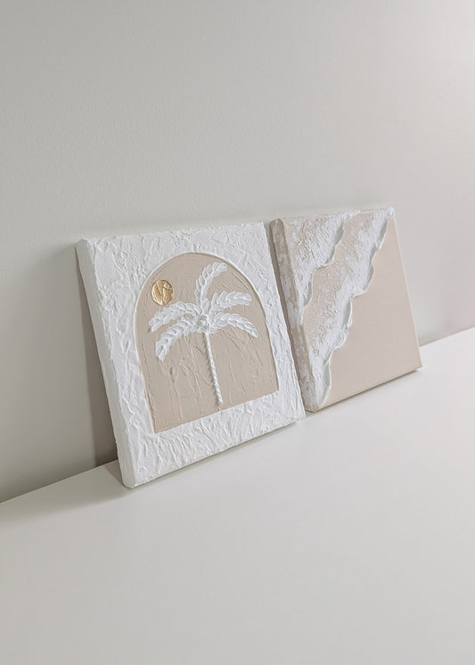Two decorative wall art pieces on a white surface with a neutral background