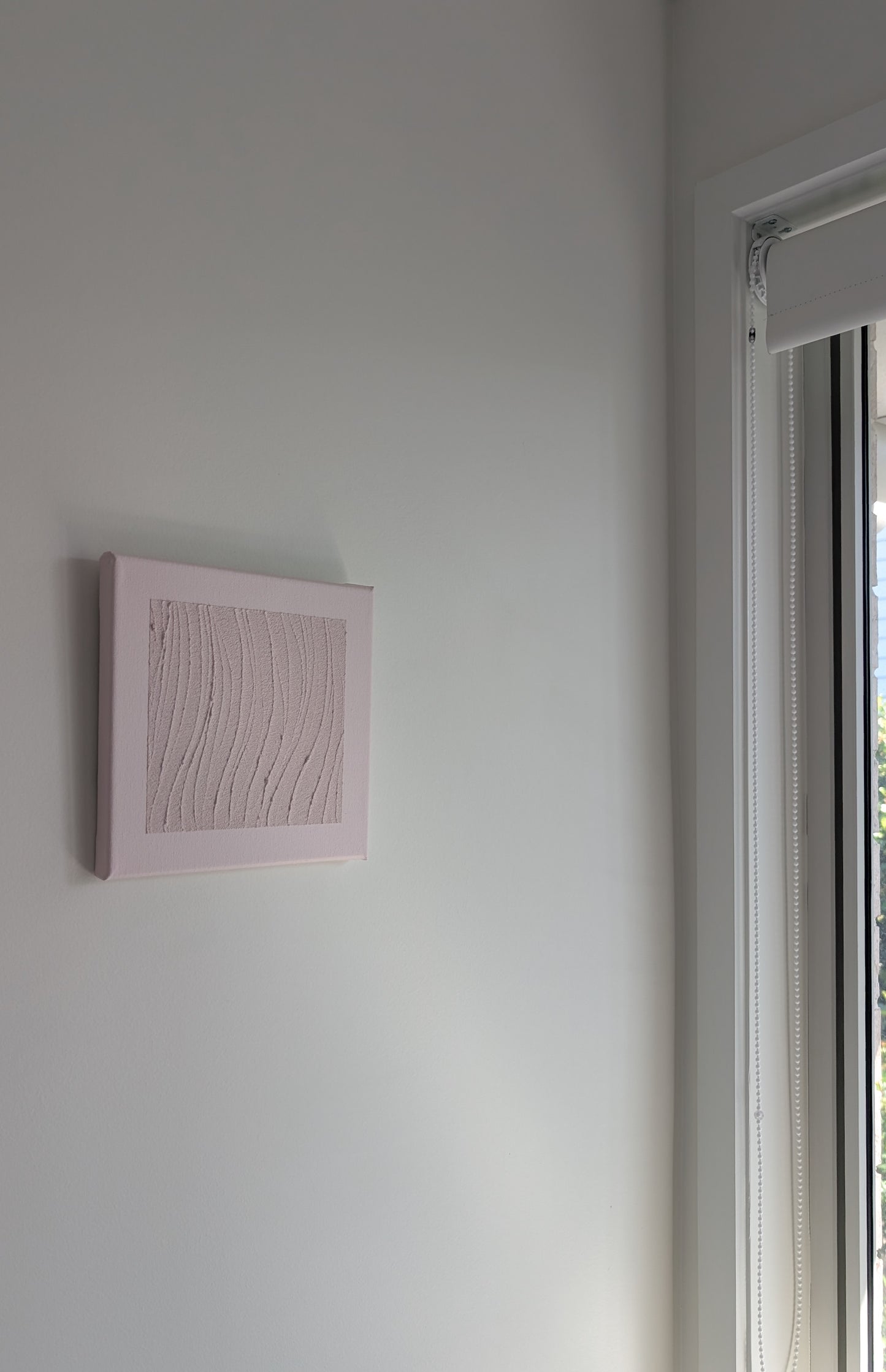 Pink abstract wall art on a white wall next to a window