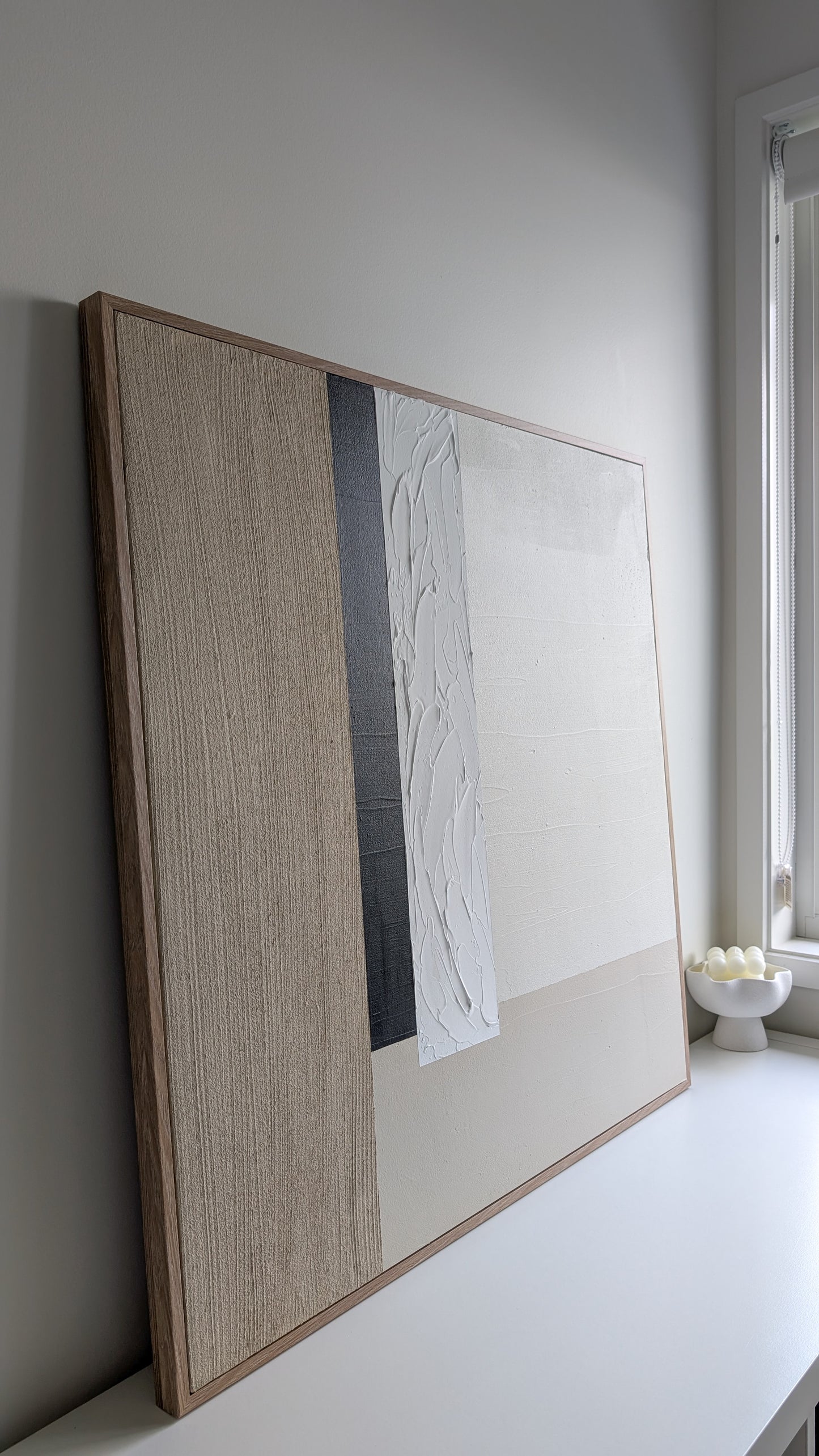 Framed artwork leaning against a wall in a minimalistic room.