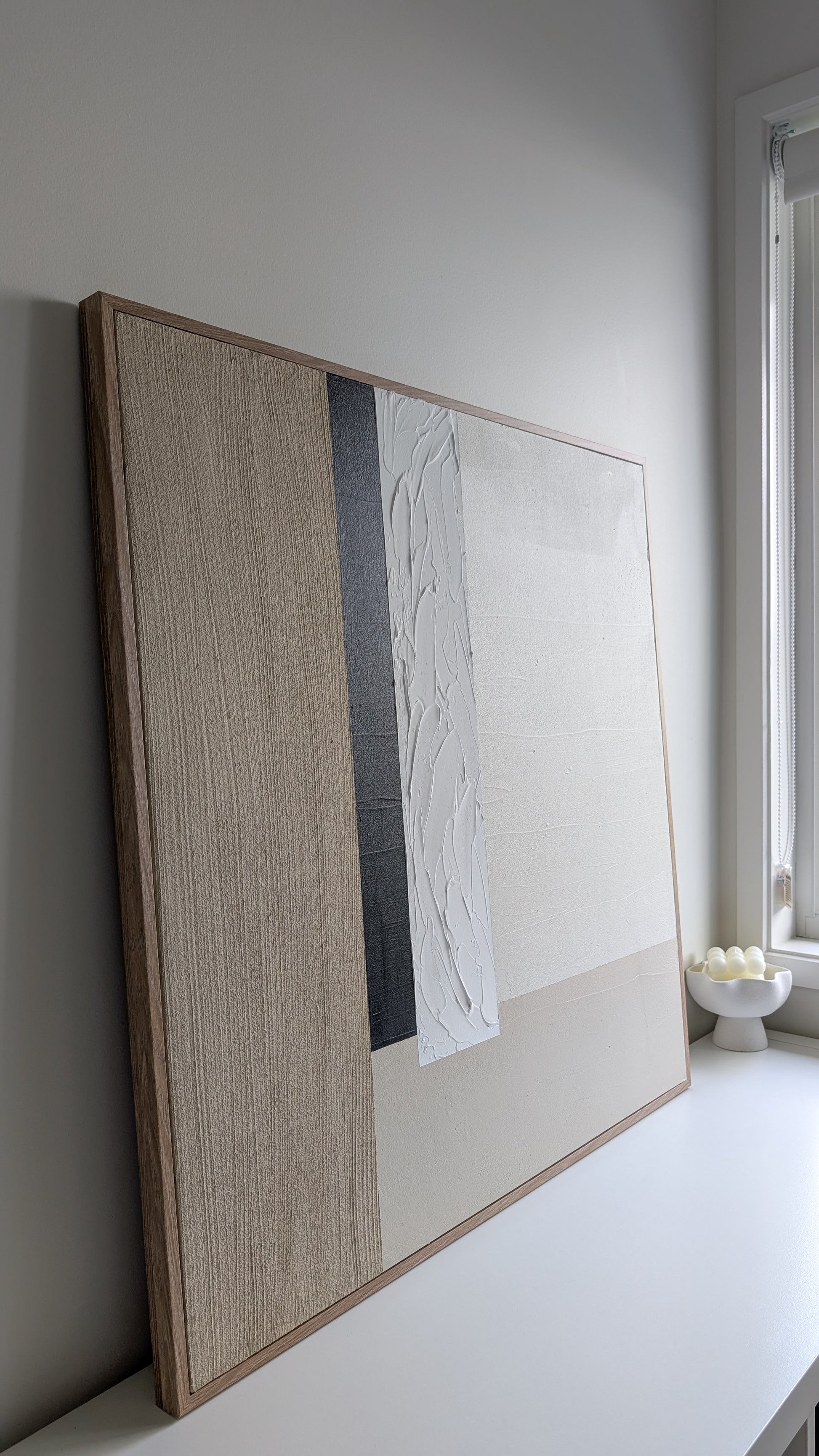 Framed artwork leaning against a wall in a minimalistic room.