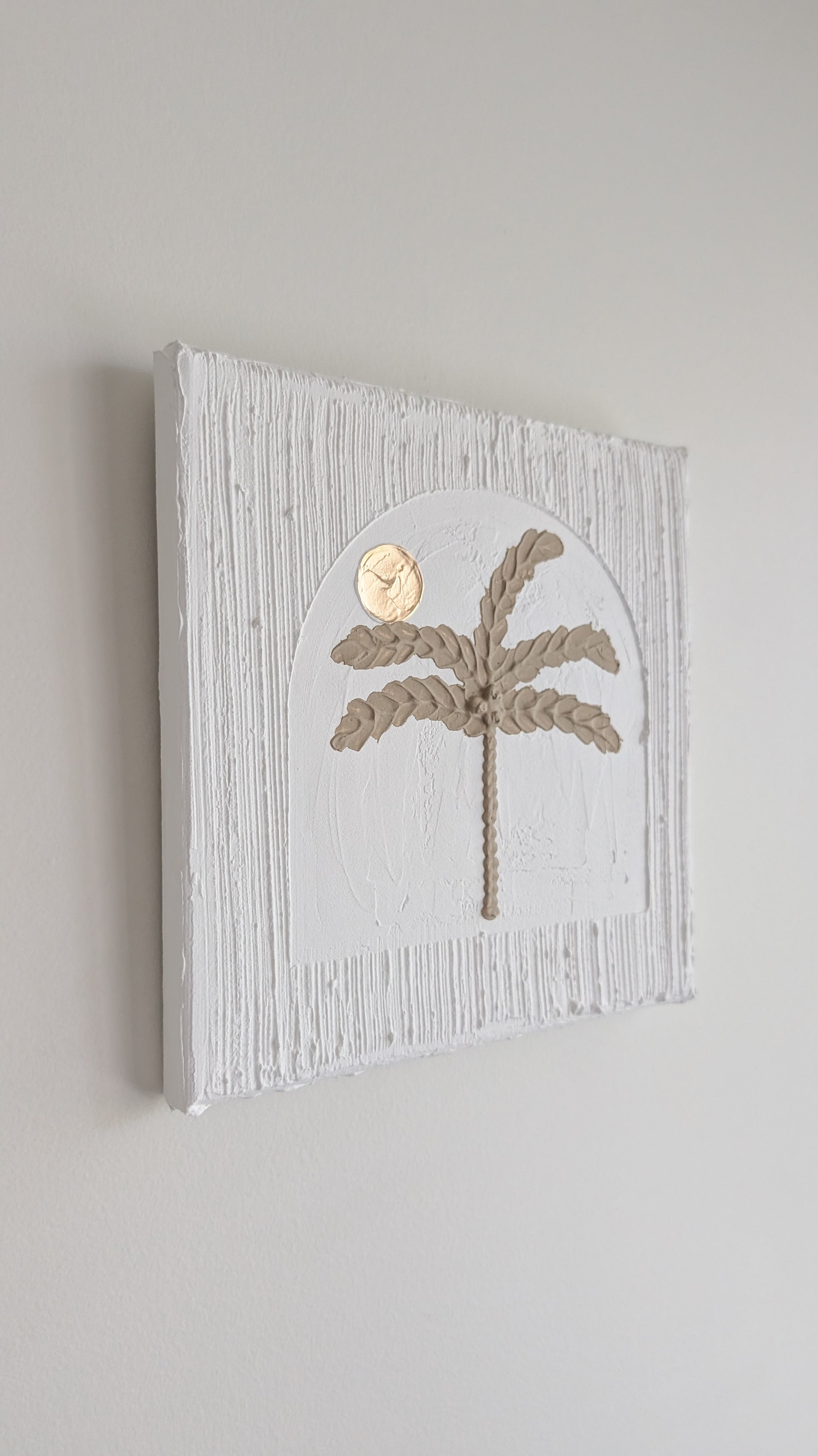 Decorative wall art with palm tree design on a light gray background