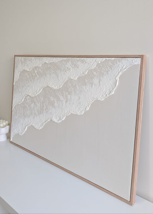 light beige ocean wave design artwork finished in a oak frame on a white wall