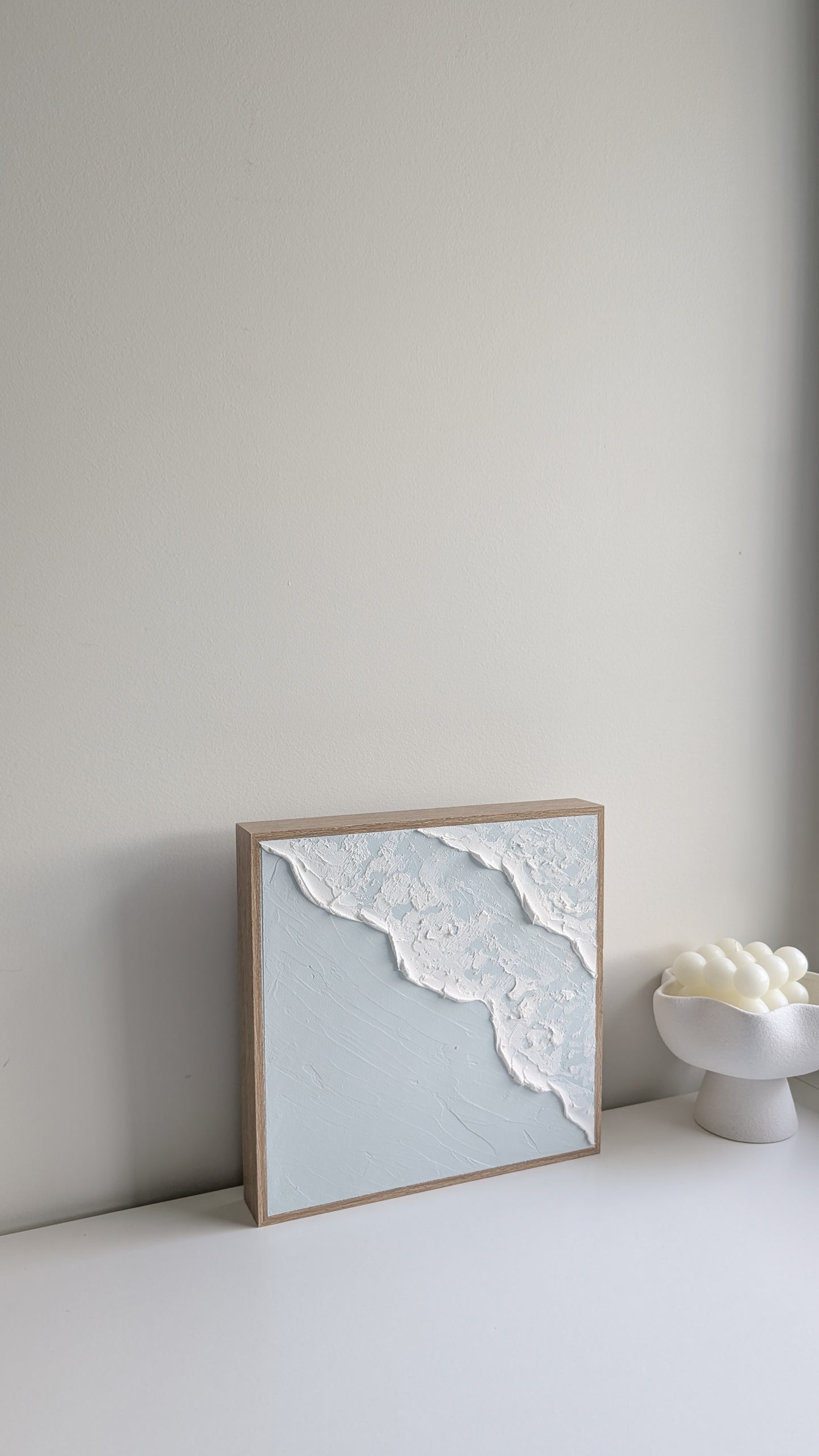 Minimalist coastal wave artwork with textured ocean foam and soft blue tones, side perspective