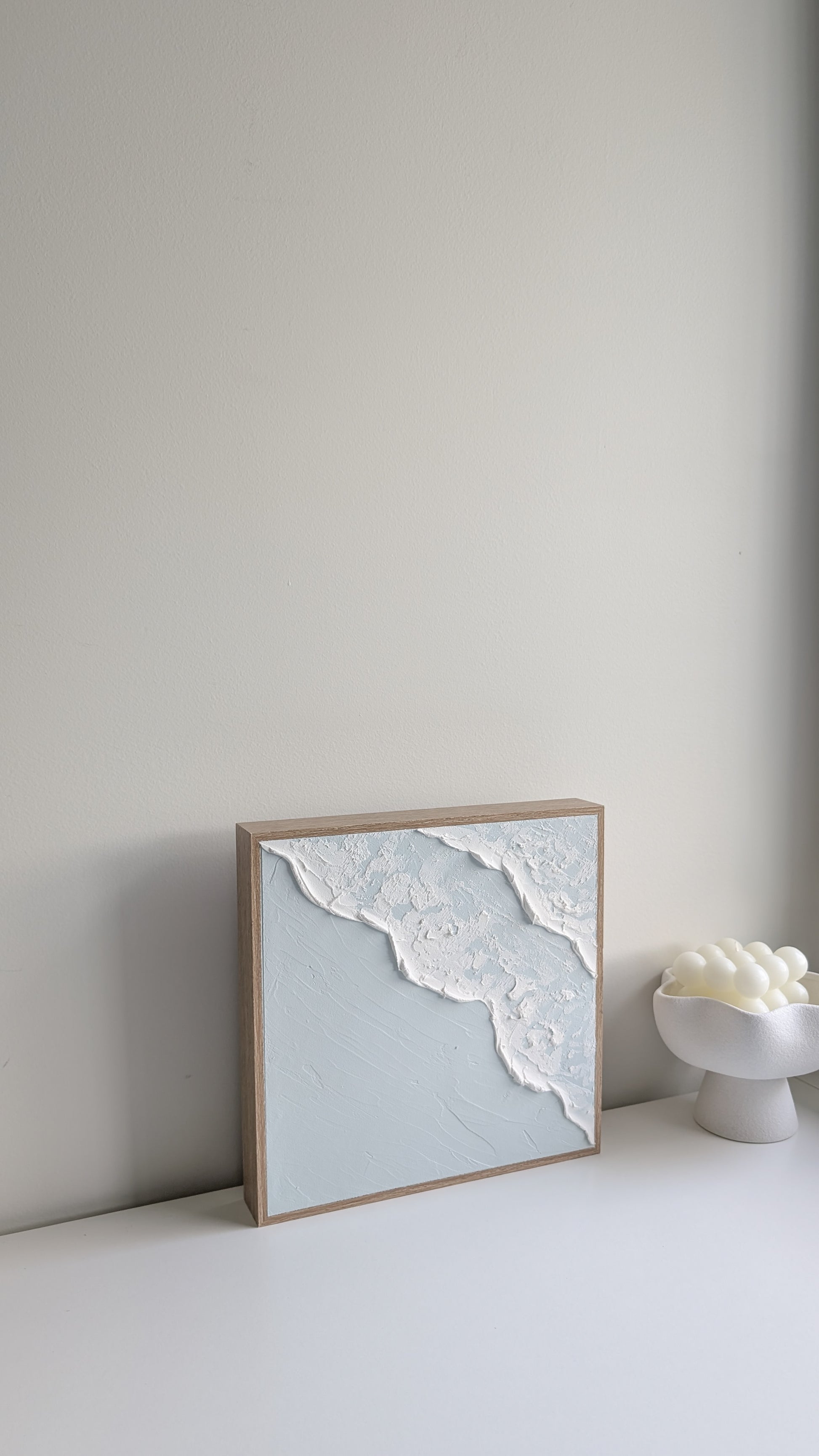 Minimalist coastal wave artwork with textured ocean foam and soft blue tones, side perspective