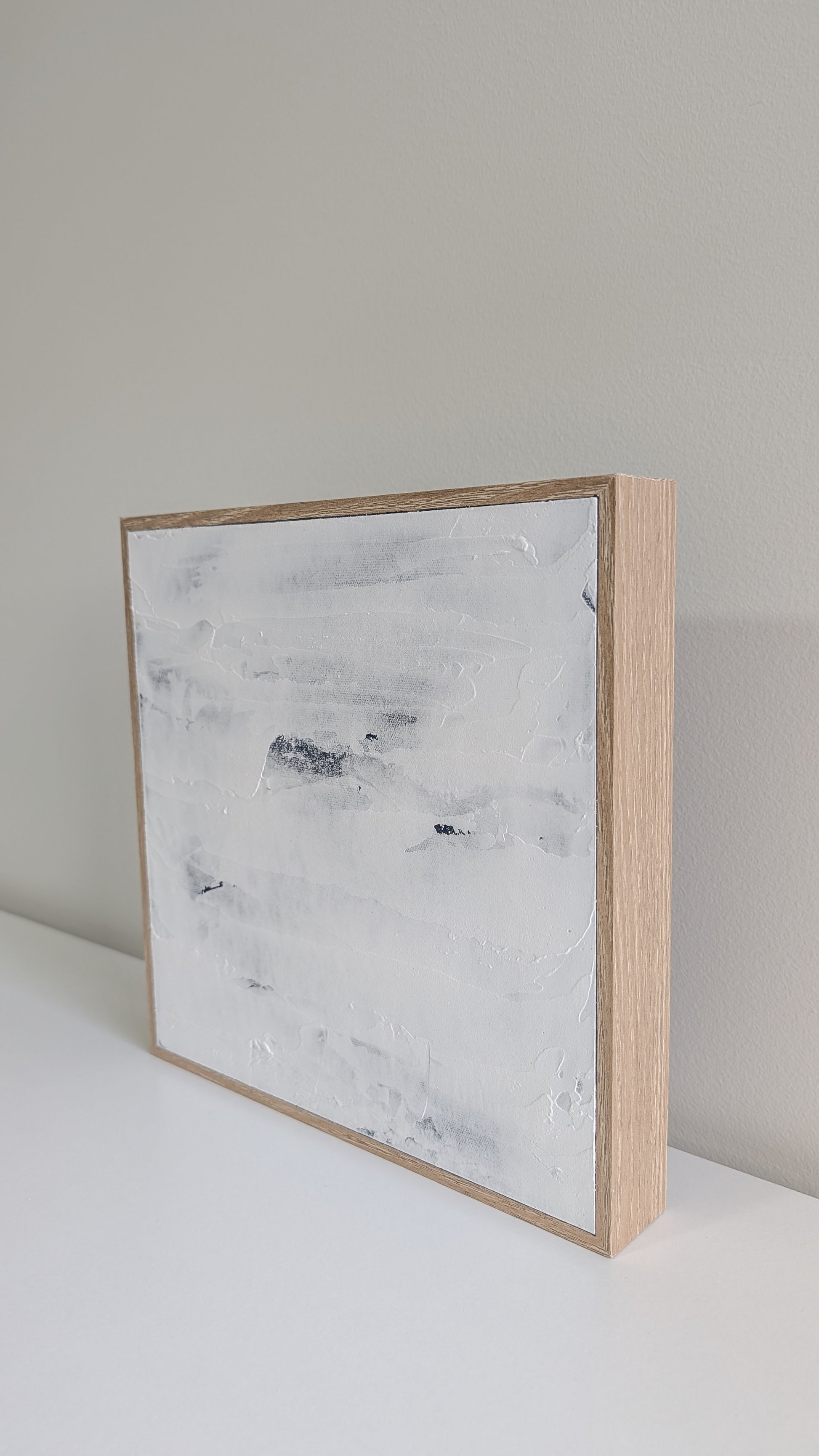 Close-up of textured coastal blue abstract artwork in natural wood frame.
