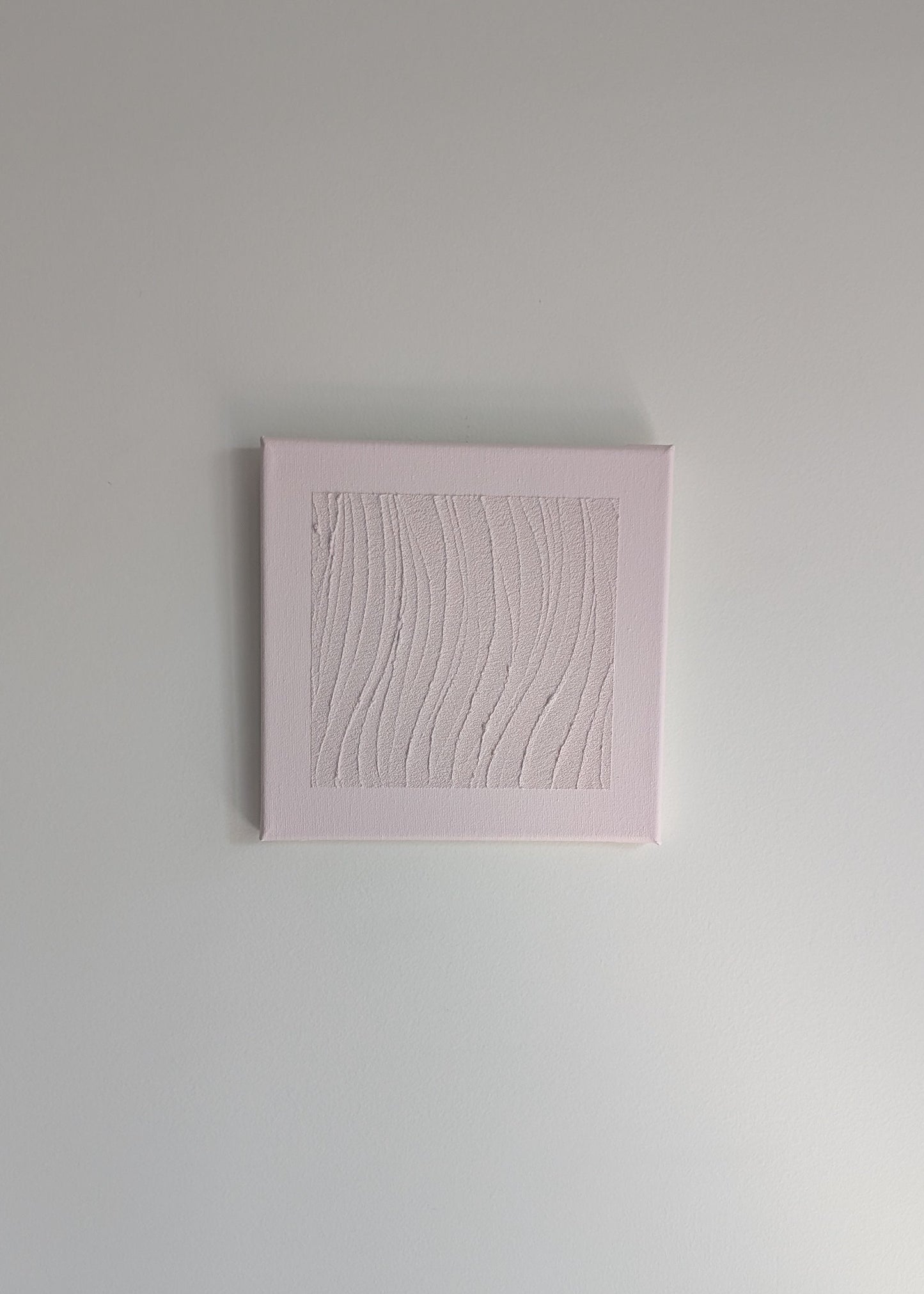 Pink textured square artwork on a light wall background