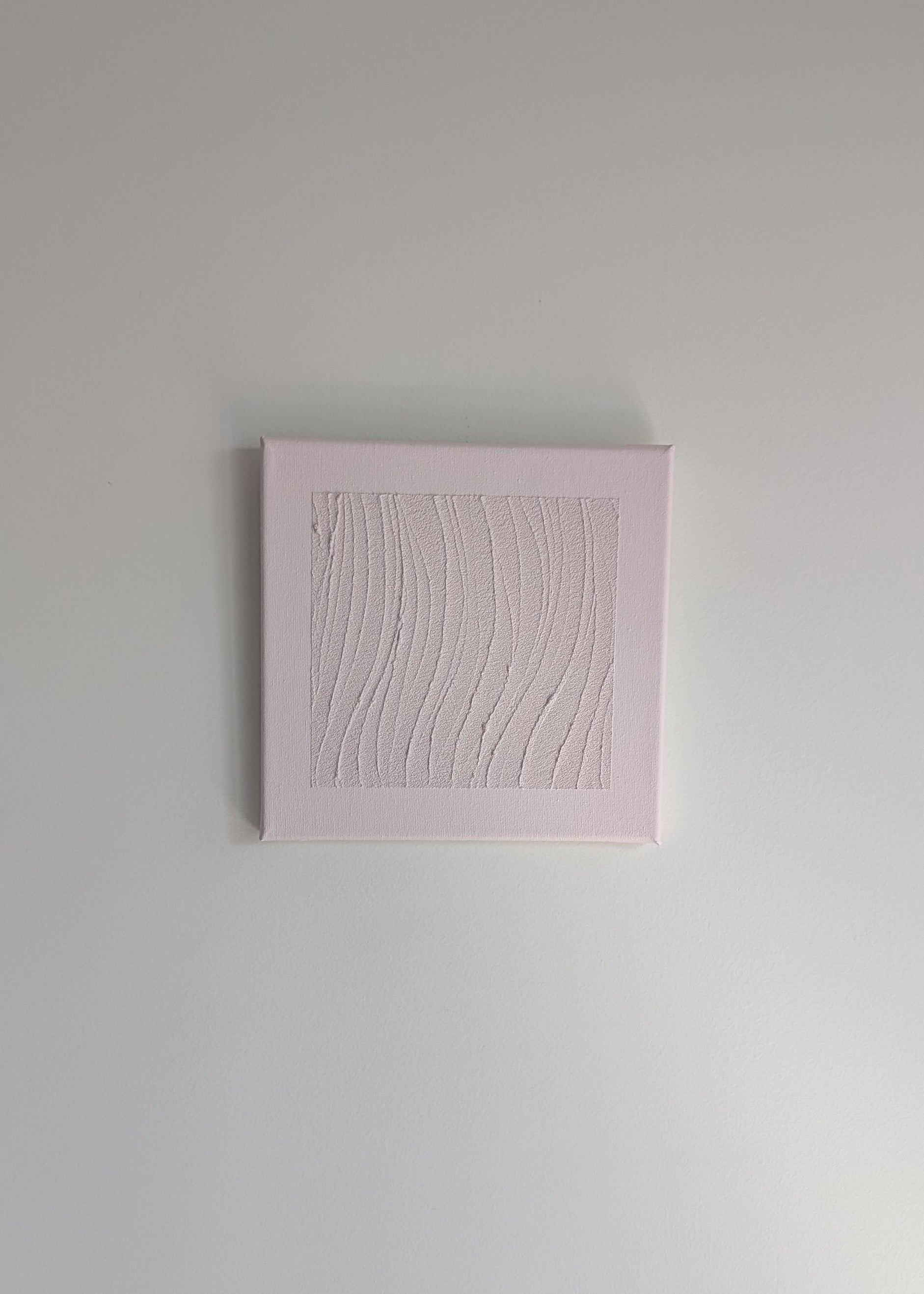 Pink textured square artwork on a light wall background