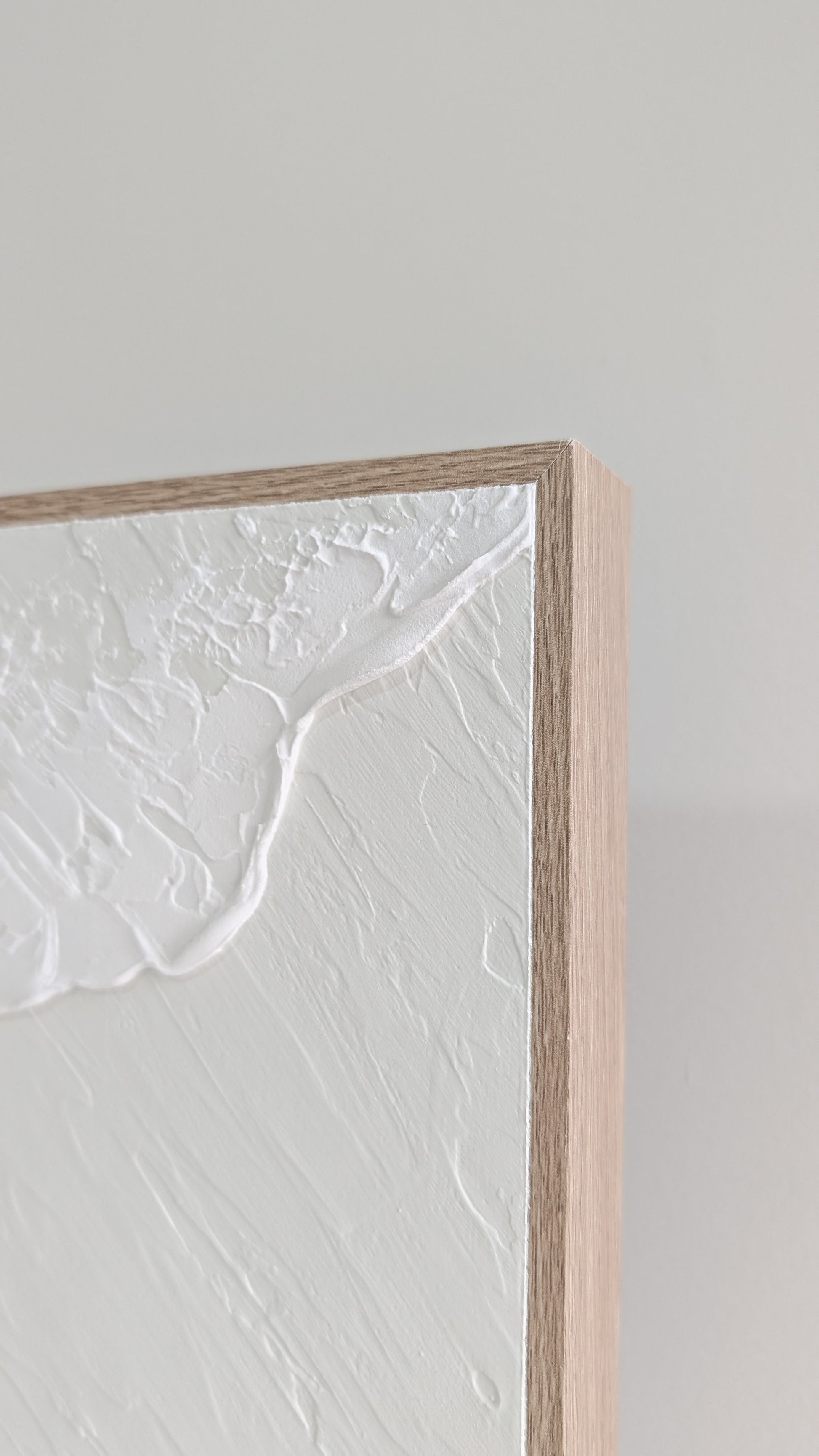 Close-up of a textured white wall with a wooden frame.