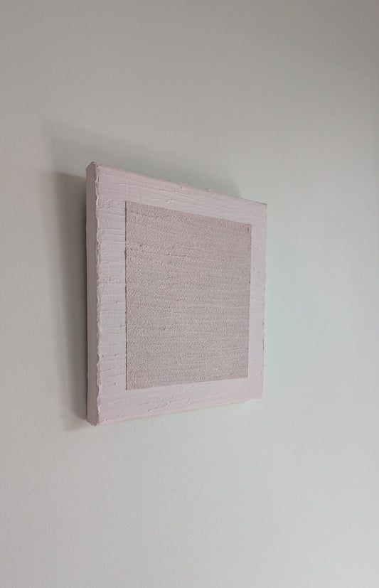 Textured pink wall art piece on a plain white wall