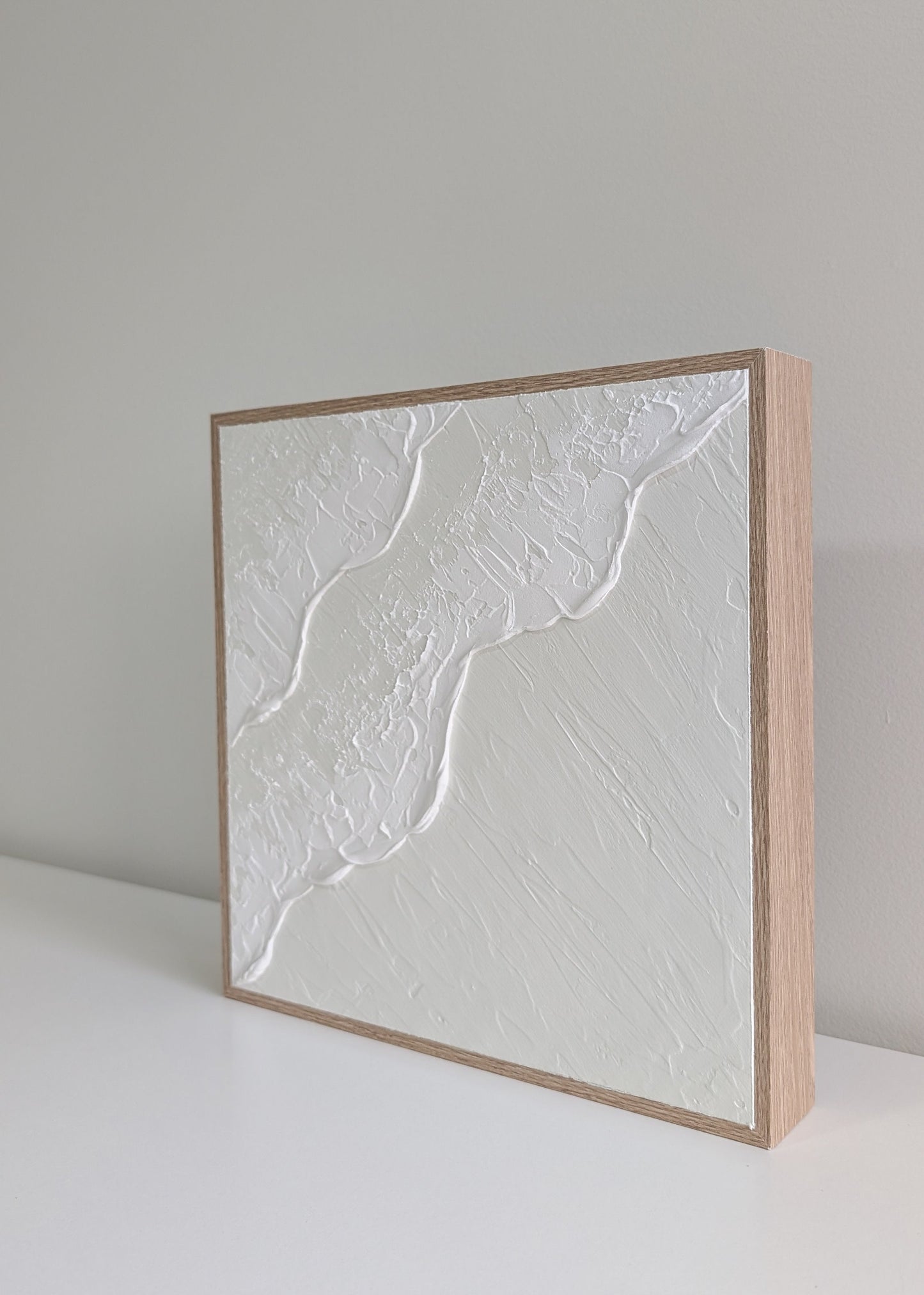 Square cream and white textured art ocean wave artwork with a wooden frame on white background