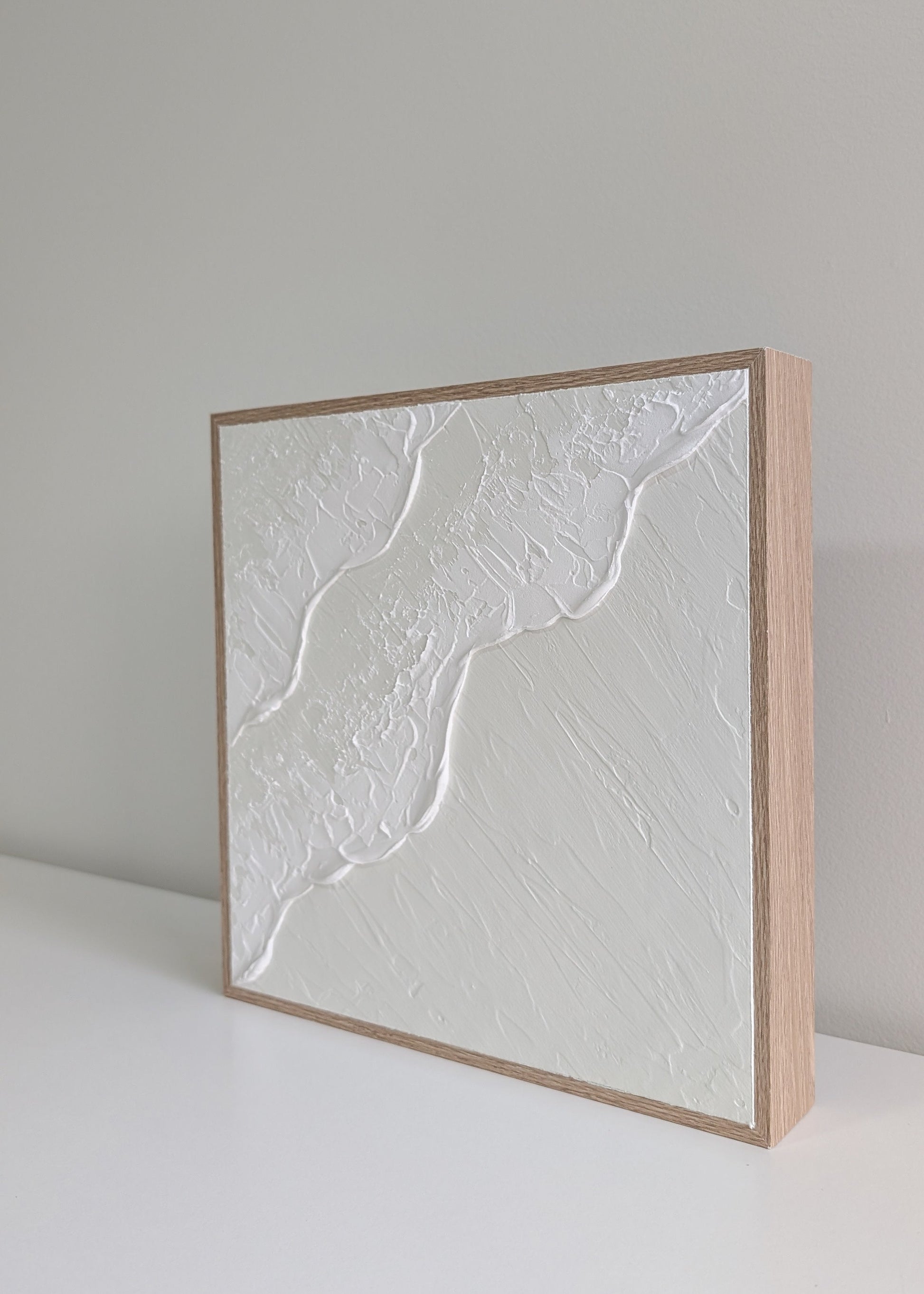 Square cream and white textured art ocean wave artwork with a wooden frame on white background