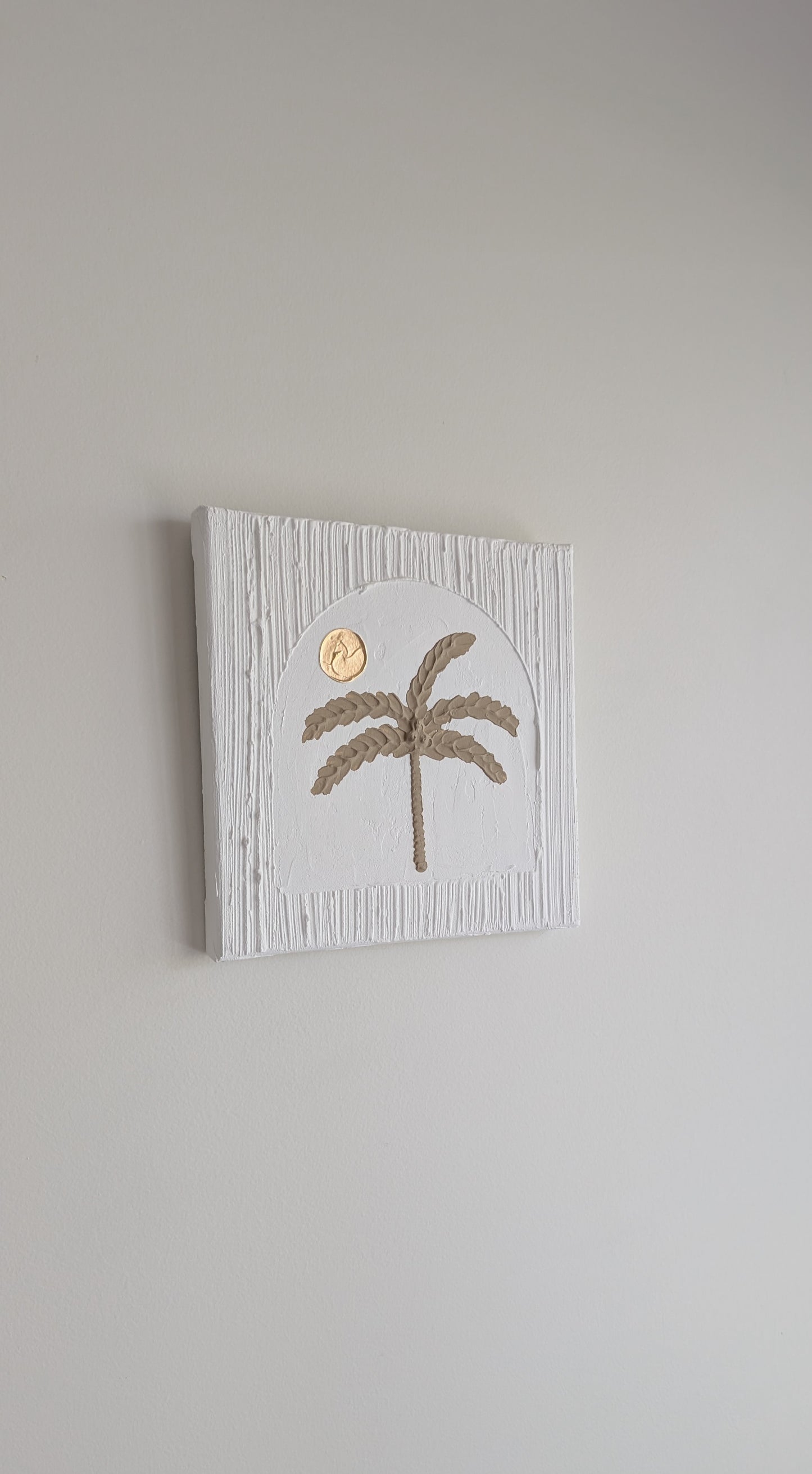 Decorative wall art with a palm tree design on a plain background
