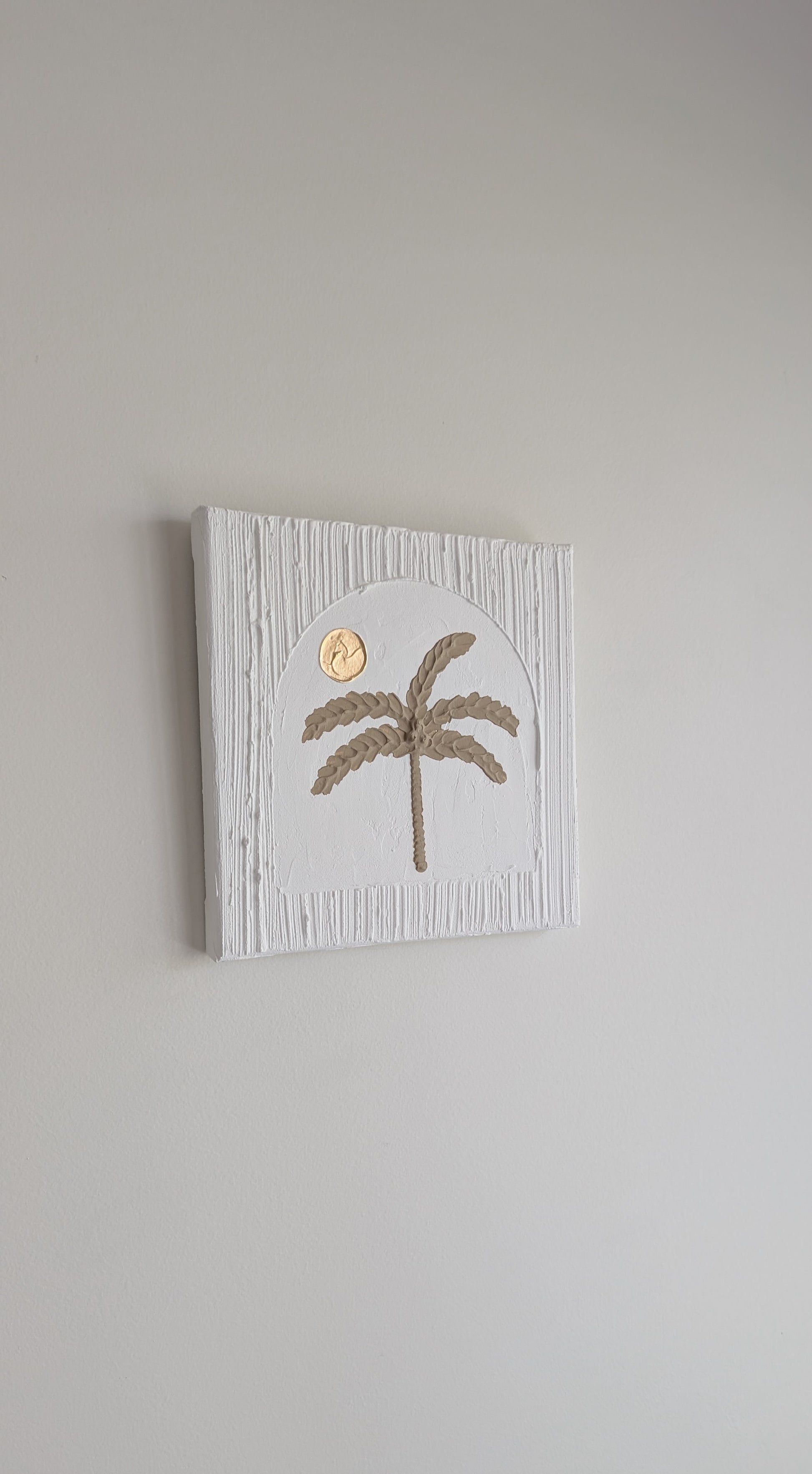 Decorative wall art with a palm tree design on a plain background