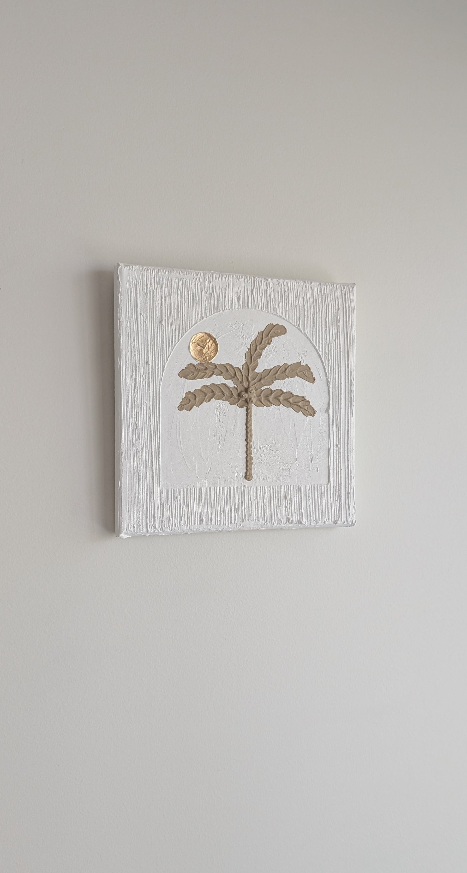 Decorative wall art with a palm tree design on a textured white background