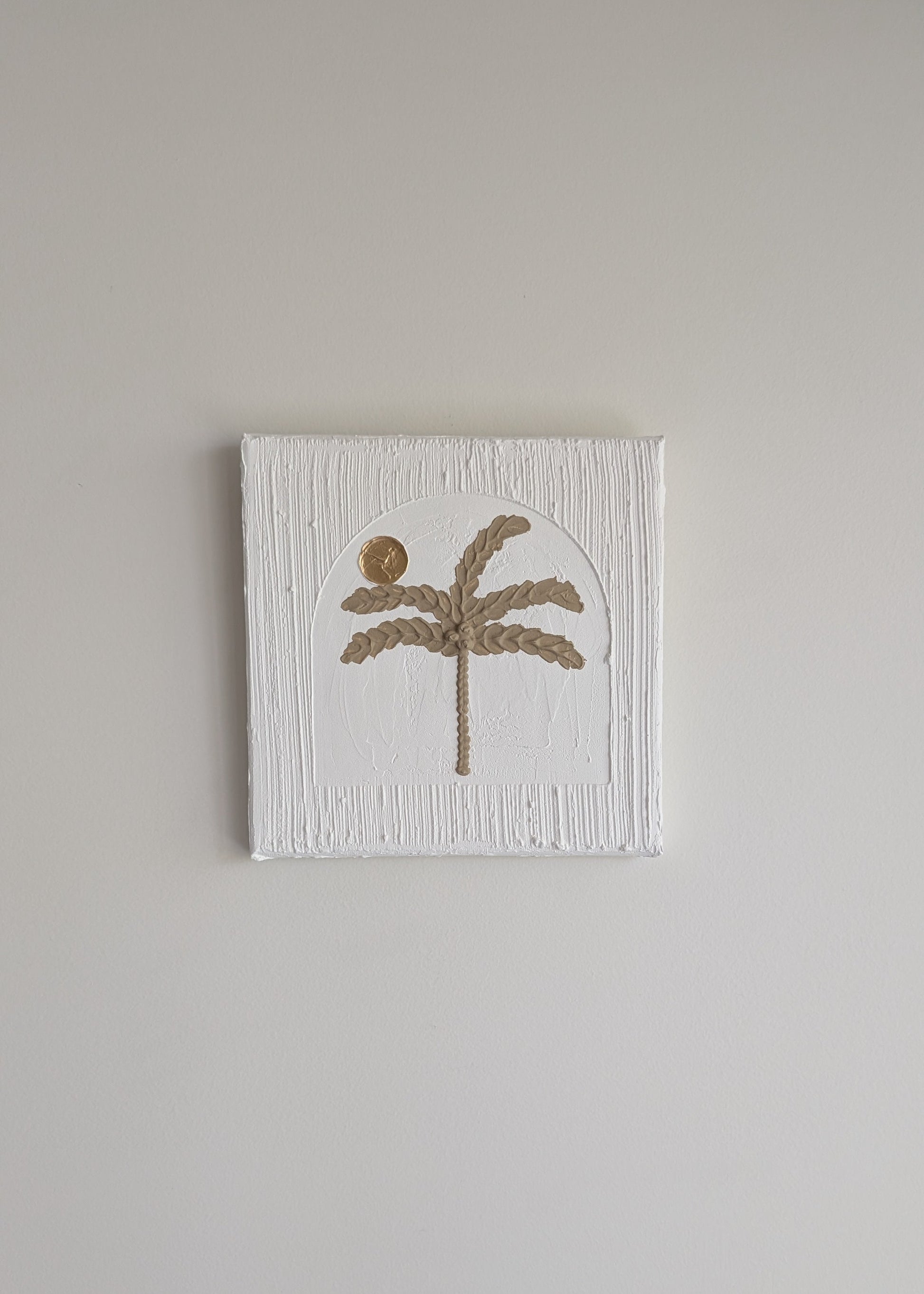Small square canvas with a palm tree design on a plain wall