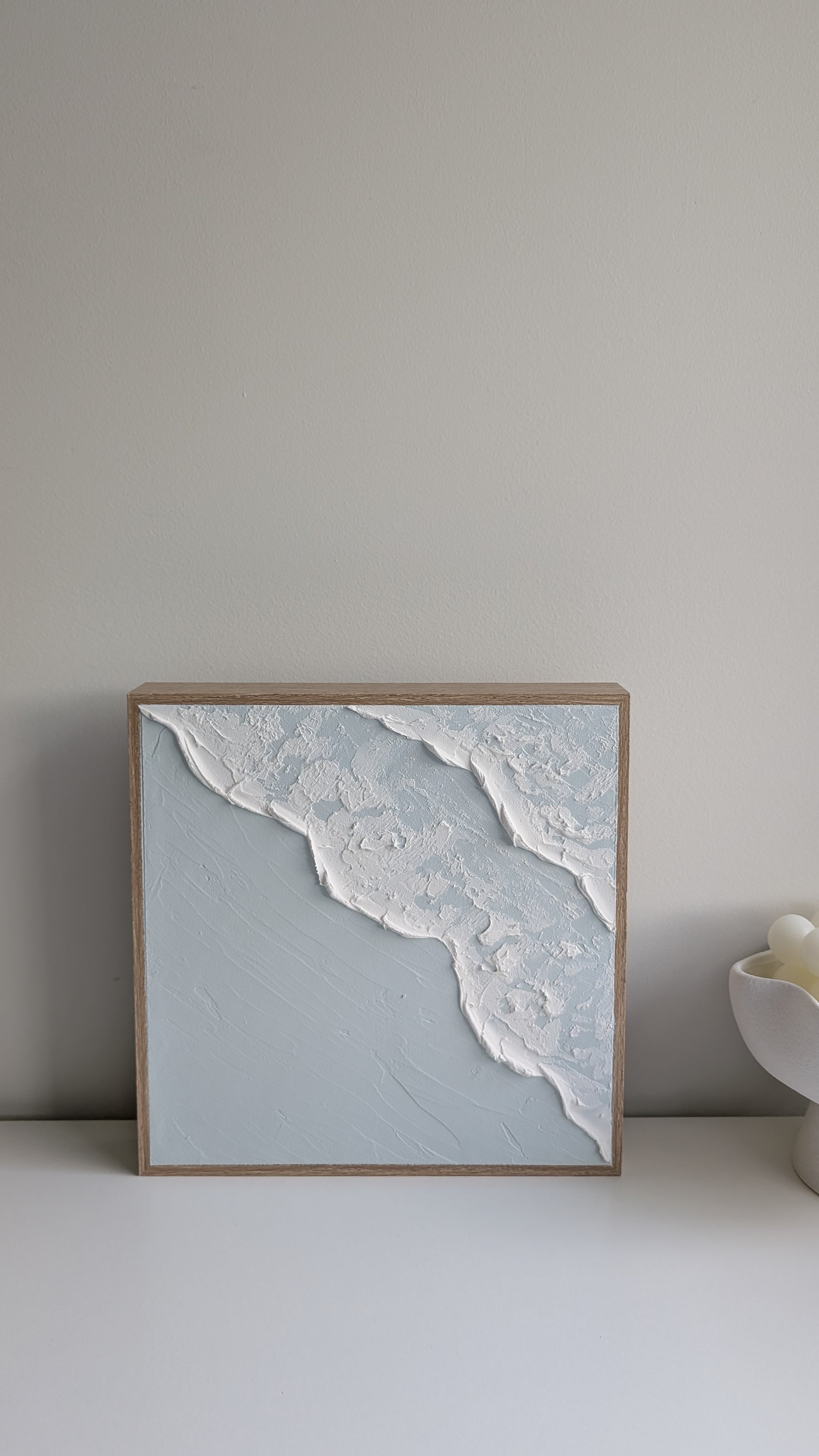 Ocean-inspired textured wall art featuring white wave detail on blue background, straight-on view